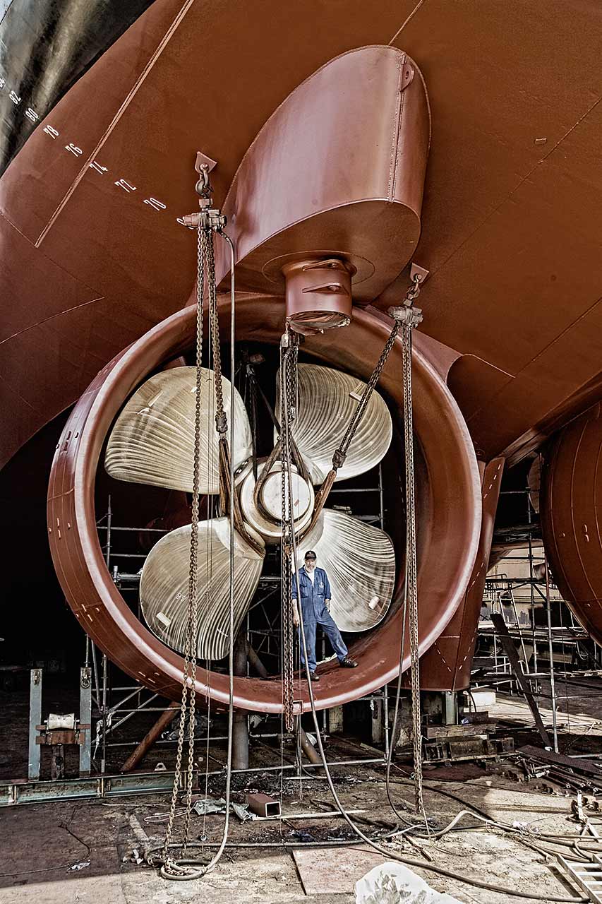 Werftarbeiter steht an der Schraube eines Schiffes